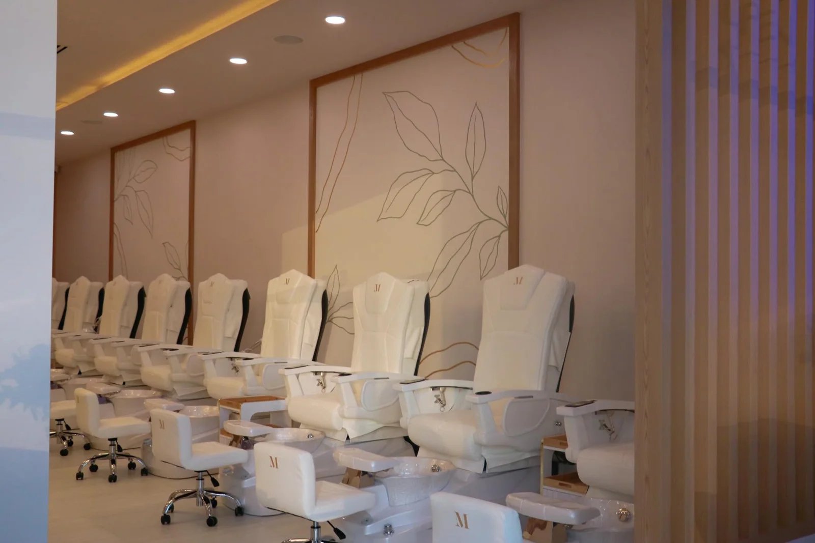 Mimi Mai's softly lit studio with white pedicure chairs and botanical wall art